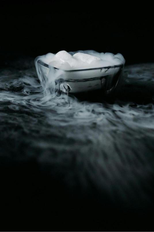 A captivating view of dry ice bubbling in warm water, generating a thick, cloud-like fog.